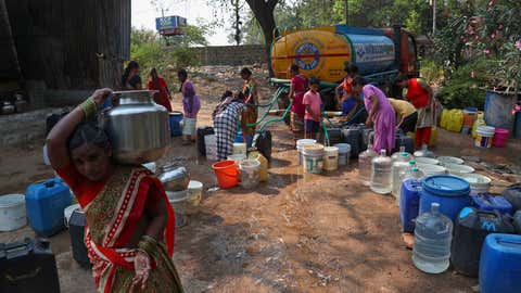 Une femme marche avec un bateau rempli d'eau après avoir récupéré dans un camion-citerne mobile dans un bidonville d'Hyderabad, en Inde, le samedi 20 mars 2021. La Journée mondiale de l'eau est célébrée chaque année le 22 mars. (AP Photo / Mahesh Kumar A. )