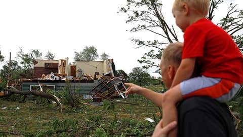 Woodridge, Ill., resident Jesse Wallace points out one of the severely damaged homes to his three-year-old son Chris Wallace, after a tornado passed through the area on Monday, June 21, 2021. (AP Photo/Shafkat Anowar)