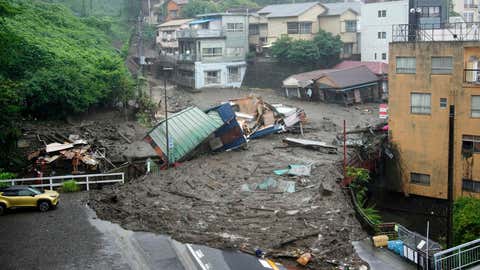 Houses are damaged by mudslide following heavy rain at Izusan district in Atami, west of Tokyo, Saturday, July 3, 2021. A powerful mudslide carrying a deluge of black water and debris crashed into rows of houses in a town west of Tokyo following heavy rains on Saturday, leaving multiple people missing, officials said. (Naoya Osato/Kyodo News via AP)