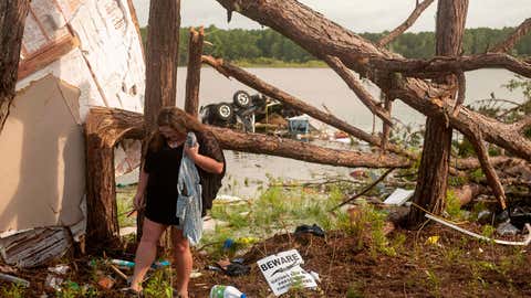 This photo provided by the U.S. Navy, Missy Lattanzie, an RV park resident, searches through her belongings that were destroyed after a tornado touched down Wednesday on Naval Submarine Base Kings Bay, on Thursday, July 8, 2021 in Kings Bay, Ga. Severe weather from Tropical Storm Elsa spurred tornado warnings in Delaware and New Jersey early Friday as the system moved over the mid-Atlantic states and into the northeastern United States.  (Mass Communication 3rd Class Aaron Xavier Saldana/U.S. Navy via AP)