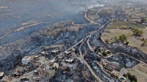 An aerial photo shows houses destroyed in a village as the fire continues to ravage forests near the Mediterranean coastal city of Manavgat, Antalya, Turkey, on Thursday, July 29, 2021. Authorities evacuated homes in southern Turkey while a blaze ignited by strong winds a forest area near the Mediterranean coastal town of Manavgat. District Governor Mustafa Yigit said residents of the four neighborhoods were displaced by the road of fires as firefighters worked to control the blaze that broke out Wednesday. It was not immediately clear what caused the fire but authorities said the nearby resorts were not affected. (Suat Metin / IHA through AP)