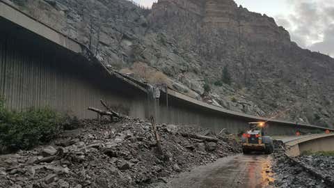 In this photo provided by the Colorado Department of Transportation, equipment works to clear mud and debris from a mudslide on Interstate-70 through Glenwood Canyon, Colo., on Friday, July 30, 2021. Authorities say more than 100 people had to spend the night on the highway, including nearly 30 who took refuge inside a highway tunnel along I-70 in Glenwood Canyon after rain over an area burned by a wildfire triggered the mudslides in Western Colorado. The people were caught with their vehicles Thursday night, July 29, 2021 and it took crews nine hours to carve out a path through the mud to reach them about 6:30 a.m. Friday, Garfield County Sheriff's Office spokesman Walt Stowe said. (Colorado Department of Transportation via AP)