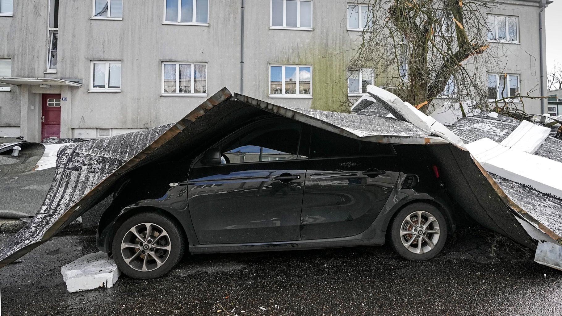 Debris covers a car after Storm Dudley blew a roof of an apartment house onto a street in Gelsenkirchen, Germany, Thursday, Feb. 17, 2022. (AP Photo/Martin Meissner)