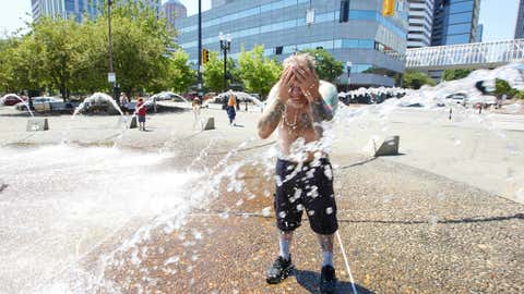 Matthew Carr cools off in the Salmon Street Springs fountain before returning to work cleaning up trash on his bicycle in Portland, Ore., Tuesday, July 26, 2022. (AP Photo/Craig Mitchelldyer)