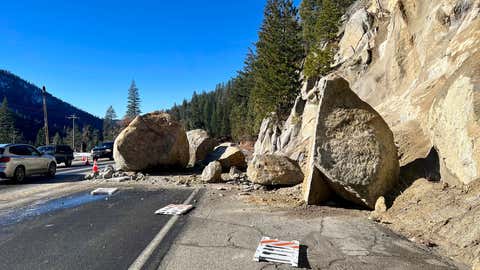 In this photo provided by Caltrans District 3, several large boulders that fell onto Highway 50 lie in the street just east of Kyburz during a storm in El Dorado National Park, California, Sunday, Jan. 1, 2023. No vehicles were hit. (Caltrans District 3 via AP)