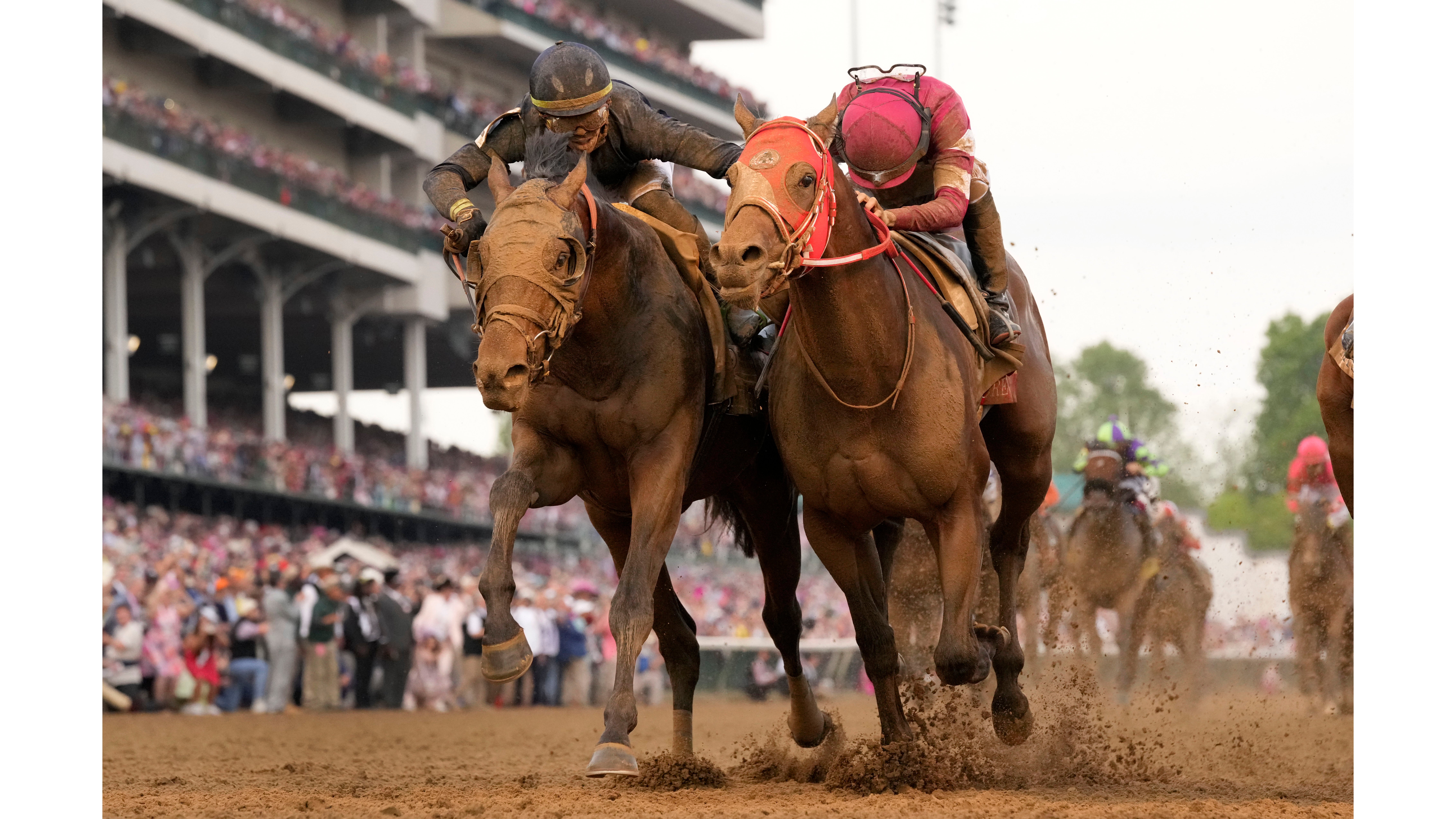 Jockey Tyler Gaffalione riding Sierra Leone, left, reaches toward Ryusei Sakai riding Forever Young as they head to the finish line to finish second and third respectively in the 150th running of the Kentucky Derby horse race at Churchill Downs Saturday, May 4, 2024, in Louisville, Ky. (AP Photo/Jeff Roberson)