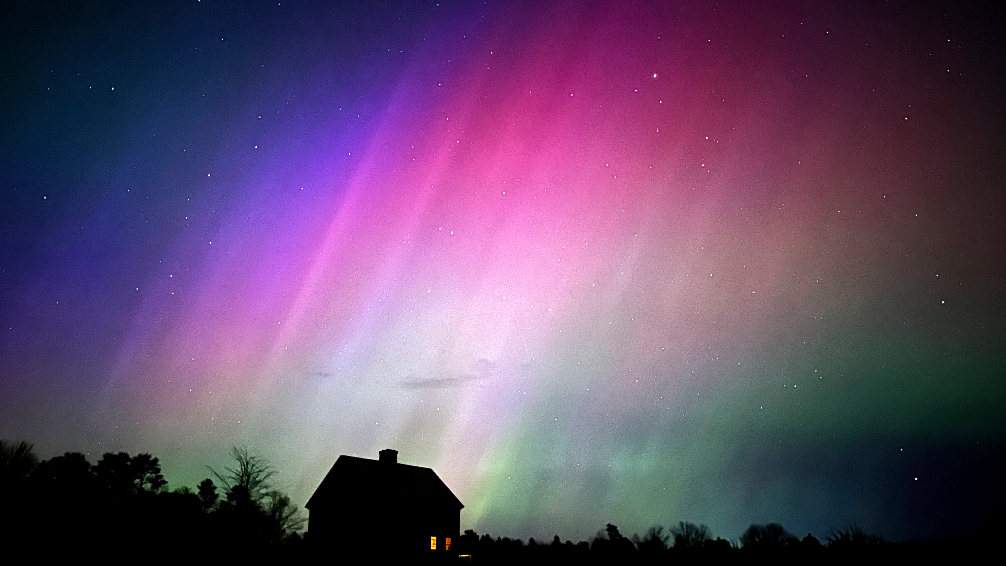 The northern lights flare in the sky over a farmhouse, late Friday, May 10, 2024, in Brunswick, Maine. (AP Photo/Robert F. Bukaty)