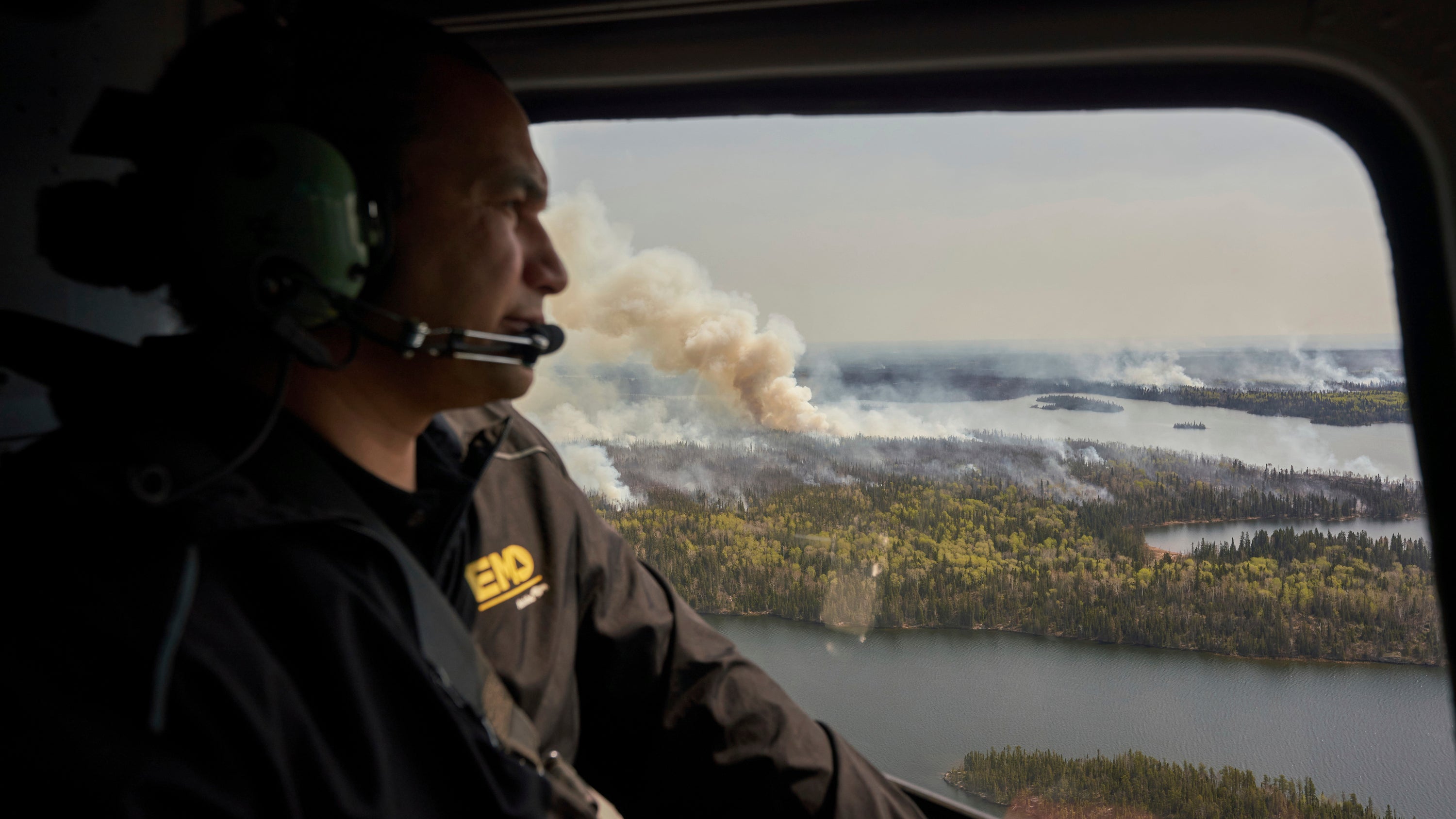 Manitoba Premier Wab Kinew surveys wildfires burning in northern Manitoba from a helicopter on Tuesday, May 14, 2024.  (David Lipnowski/The Canadian Press via AP)