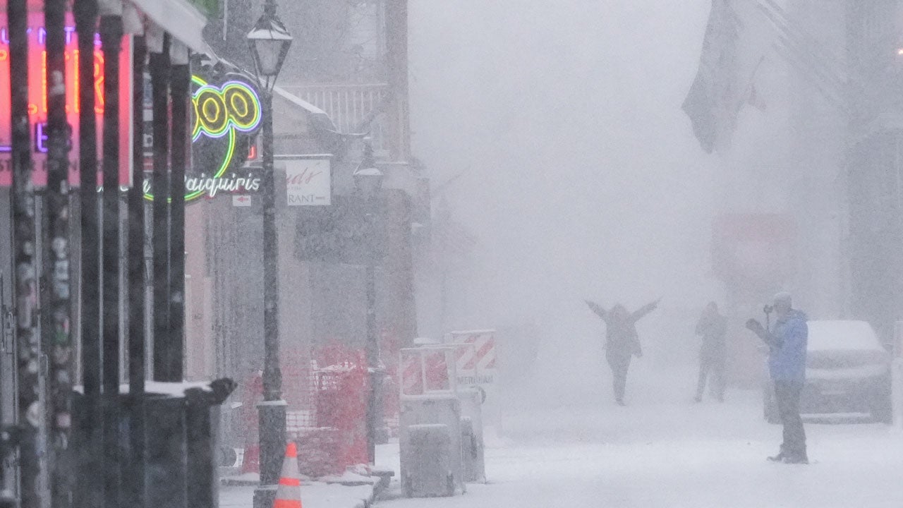 People walk around on Bourbon Street as snow falls in the French Quarter in New Orleans, Tuesday, Jan. 21, 2025. (AP Photo/Gerald Herbert)