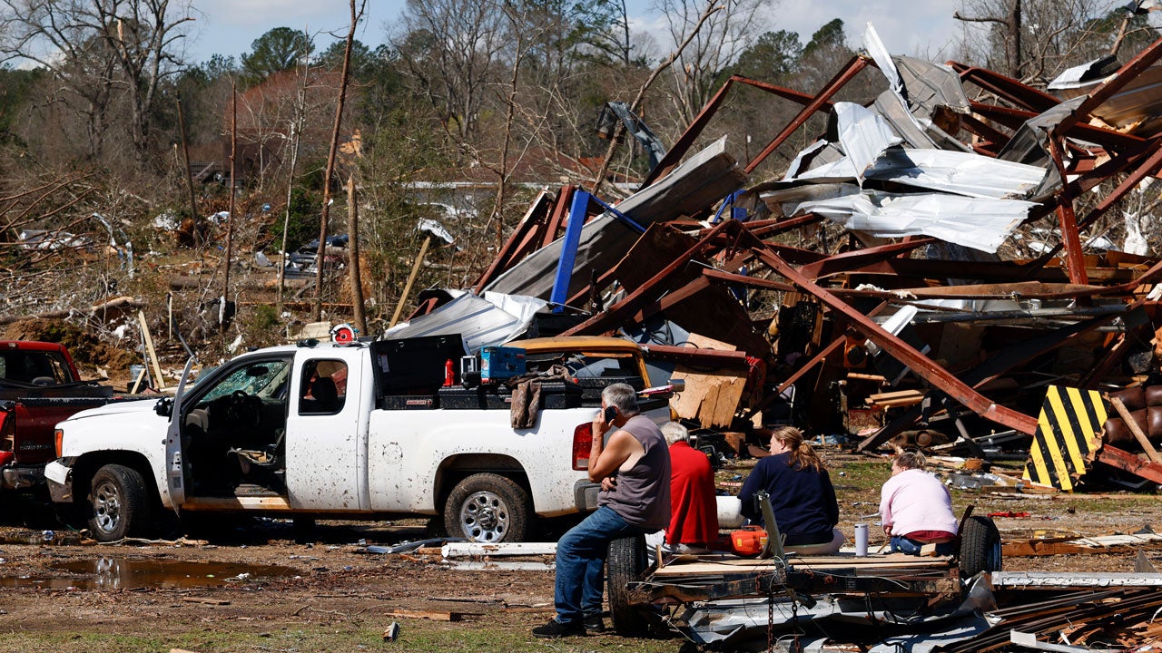 Friends and family members take a break as they search for belongings in the damage after a tornado passed through the area, Sunday, March 16, 2025, in Plantersville, Alabama. (AP Photo/Butch Dill)