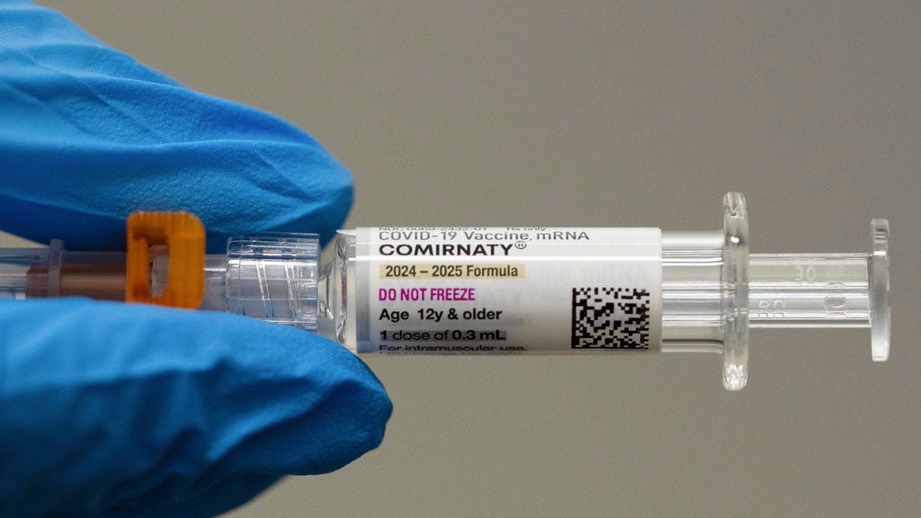 FILE - A pharmacist holds a Pfizer and BioNTech COVID-19 vaccine shot on Thursday, April 24, 2025, in Portland, Oregon.