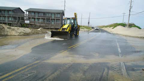 A front-end loader pushes seawater from Hurricane Erin down NC-12 in Buxton, North Carolina, on Wednesday, Aug. 20, 2025. (AP Photo/Allen G. Breed)