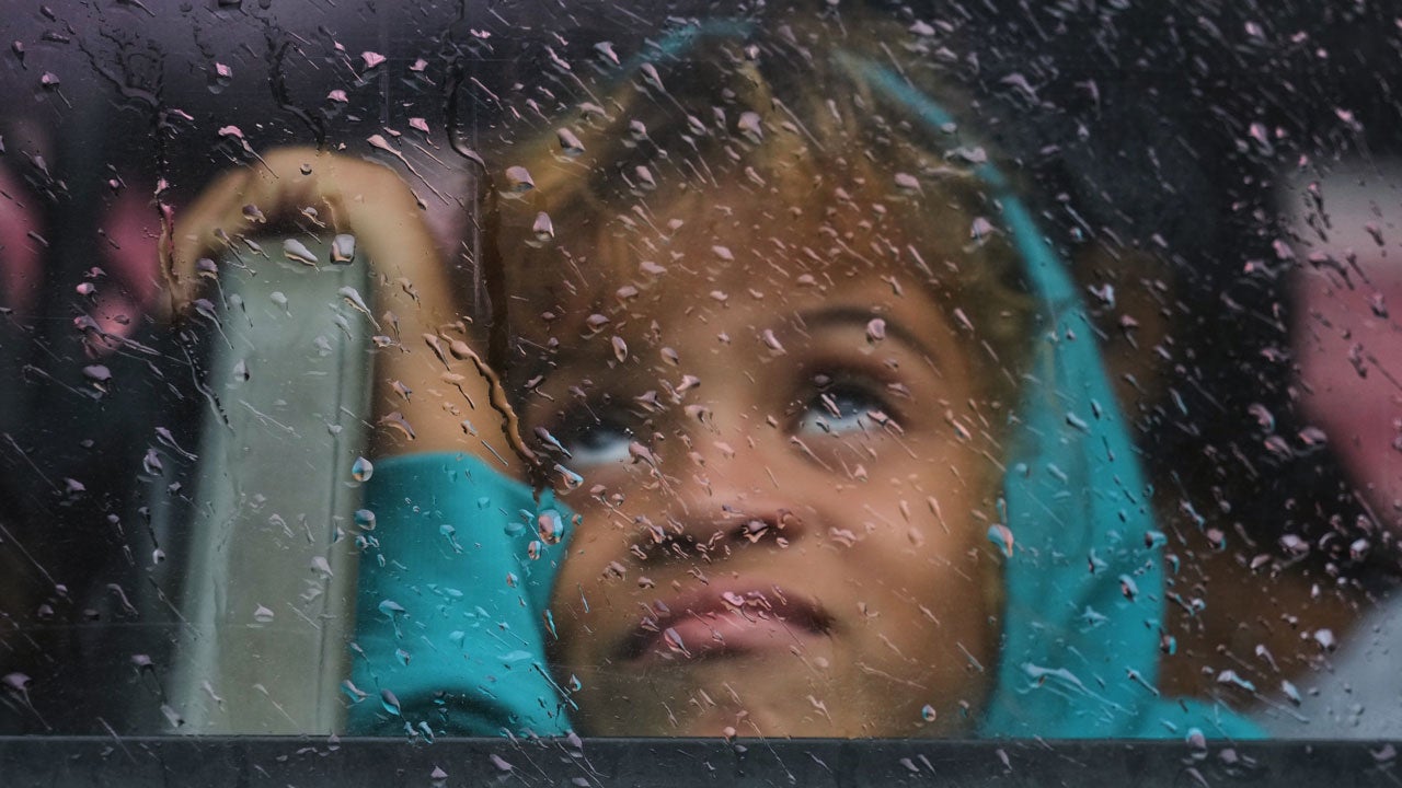 A girl looks out a rain-splattered bus window as she is evacuated before the arrival of Hurricane Melissa in Canizo, a community in Santiago de Cuba, Tuesday, Oct. 28, 2025. (AP Photo/Ram&oacute;n Espinosa)