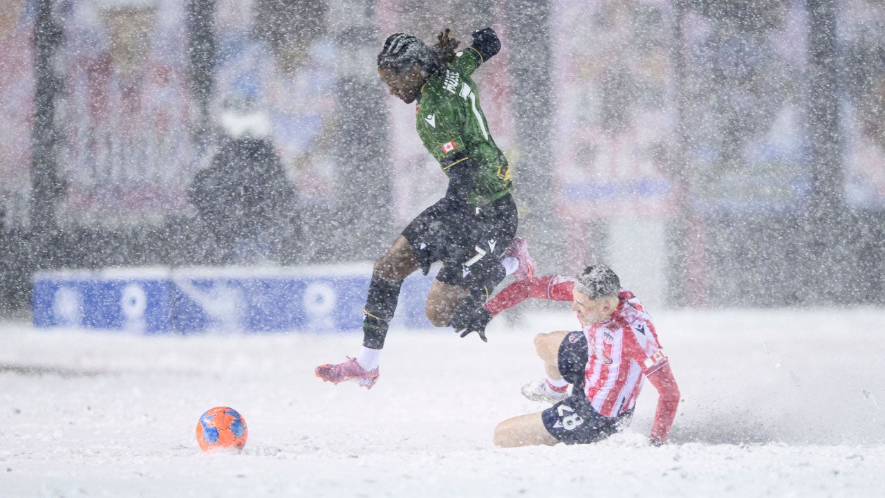 Cavalry FC's Ali Musse, left, leaps over Atletico Ottawa's Lo&iuml;c Cloutier, right, as he fights to regain possession of the ball during the first half of Canadian Premier League finals soccer match action in Ottawa, Ontario, Sunday, Nov. 9, 2025. (Spencer Colby/The Canadian Press via AP)