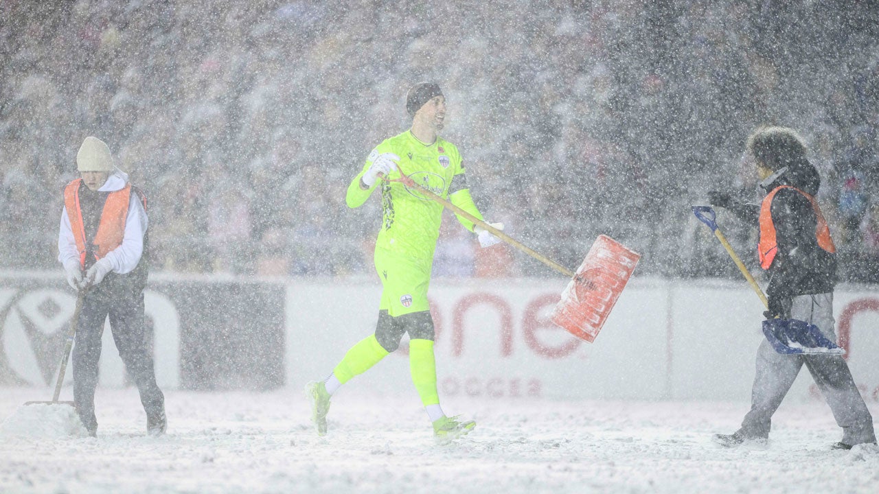 Atletico Ottawa's Nathan Ingham, center, carries a snow shovel following a break in play as officials work to clean pitch lines during first-half Canadian Premier League finals soccer match action against Cavalry FC in Ottawa, Ontario, Sunday, Nov. 9, 2025. (Spencer Colby/The Canadian Press via AP)