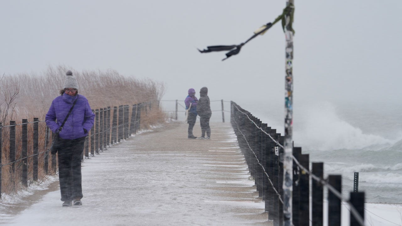 People walk along the shore of Lake Michigan in the snow Saturday, Nov. 29, 2025, in Chicago. (AP Photo/Kiichiro Sato)