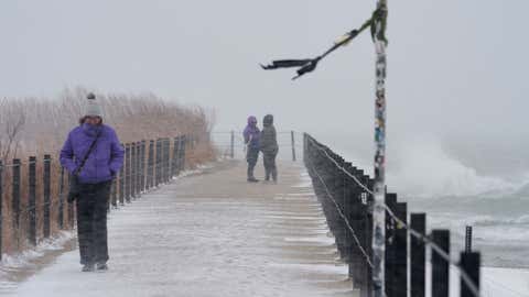 People walk along the shore of Lake Michigan in the snow Saturday, Nov. 29, 2025, in Chicago. (AP Photo/Kiichiro Sato)