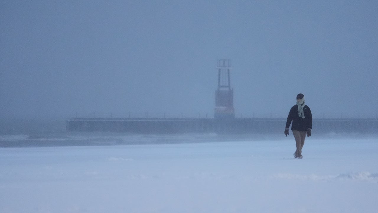 A bundled-up person walks on a beach along Lake Michigan, Saturday, Nov. 29, 2025, in Chicago. (AP Photo/Kiichiro Sato)