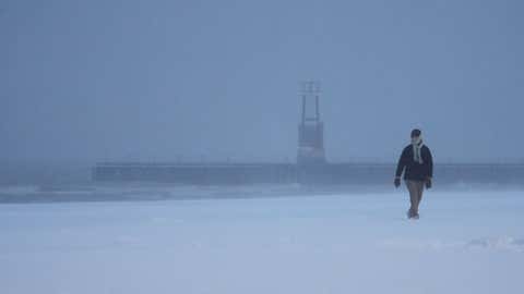 A bundled-up person walks on a beach along Lake Michigan, Saturday, Nov. 29, 2025, in Chicago. (AP Photo/Kiichiro Sato)