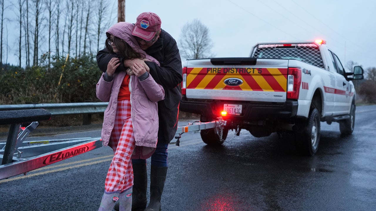 Patric Schine hugs daughter Maery, 11, after evacuating their home surrounded by flooding after heavy rains in the region Tuesday, Dec. 9, 2025, in Chehalis, Washington. (AP Photo/Lindsey Wasson)