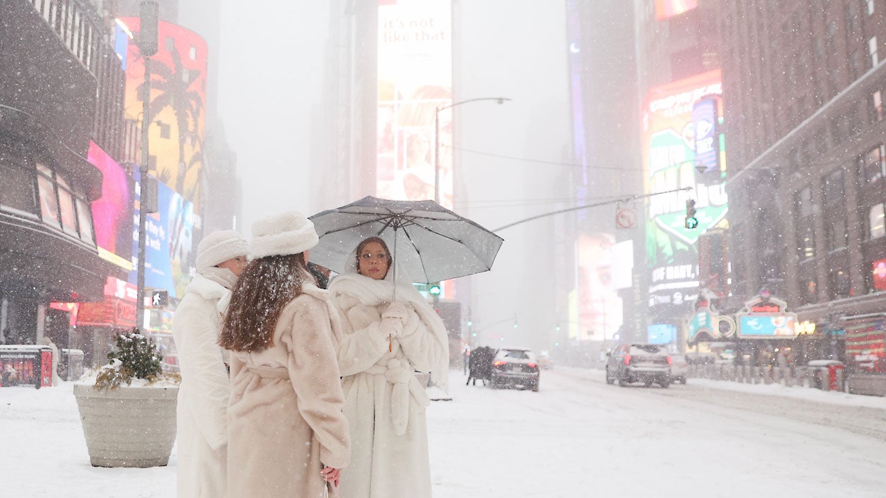 People wait to cross the street in Times Square during a winter storm, Sunday, Jan. 25, 2026, in New York. (AP Photo/Heather Khalifa)