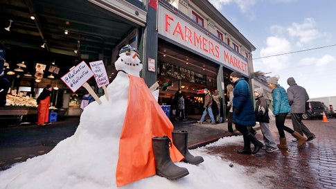 A snow sculpture is dressed as the fish mongers working behind as people walk into the Pike Place Market in near-freezing weather Tuesday, Feb. 5, 2019, in Seattle. Winter weather closed schools and disrupted travel across much of the West, with ice and snow stretching from Seattle to Arizona. The Pacific Northwest shivered Tuesday under colder-than-normal conditions as snow and treacherous conditions led to another day of school closures. (AP Photo/Elaine Thompson)