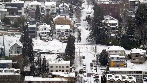 Streets, homes and cars remain snow-covered on one of Seattle's steeper hills, Queen Anne, Monday, Feb. 11, 2019. Schools and universities closed across Washington state and the Legislature cancelled all hearings as the Northwest dealt with snow and ice and prepared for more as a series of winter storms socked the region. (AP Photo/Elaine Thompson)