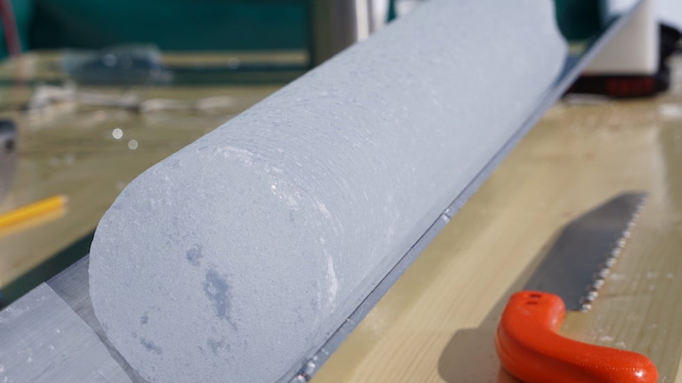 An ice core sits in the aluminum trough for processing and bagging