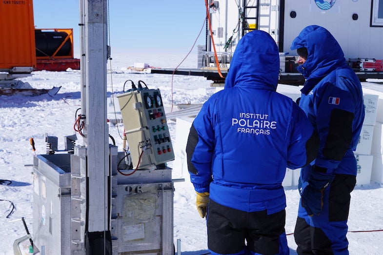 Two team members wait as the drilling piece is lowered into the borehole