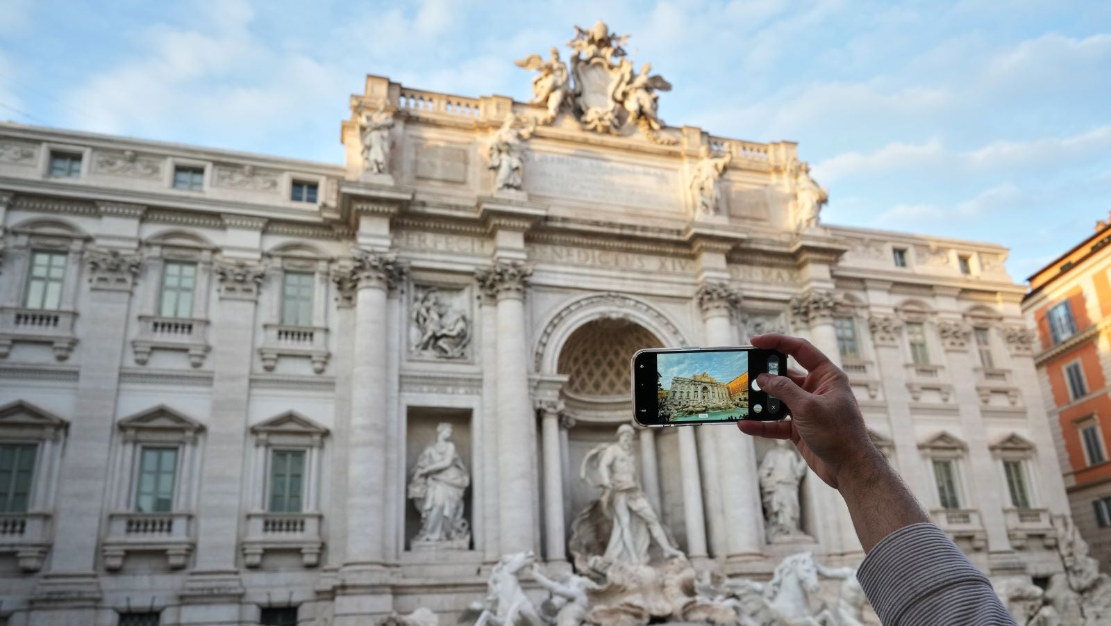 19.12.2025, Italien, Rom: Ein Besucher macht ein Foto des Trevi-Brunnens. Die Stadtverwaltung k&uuml;ndigte an, dass sie ab dem 1. Februar eine Geb&uuml;hr von zwei Euro f&uuml;r Touristen erheben wird, die sich dem Brunnen zu n&auml;hern wollen. Foto: Andrew Medichini/AP/dpa +++ dpa-Bildfunk +++