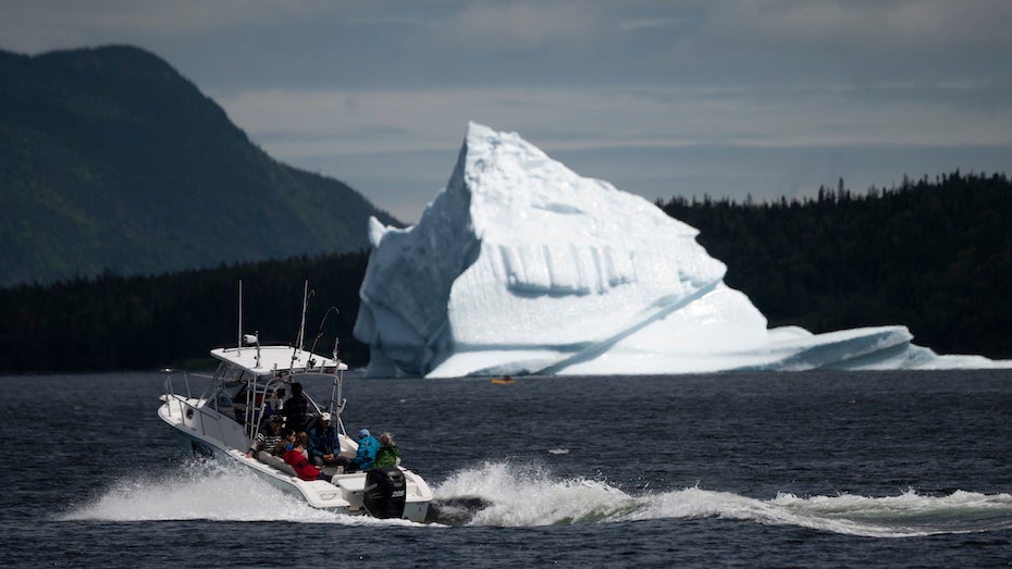 Tour guide steers boat near iceberg at Kings Point, Newfoundland, 7/5/19