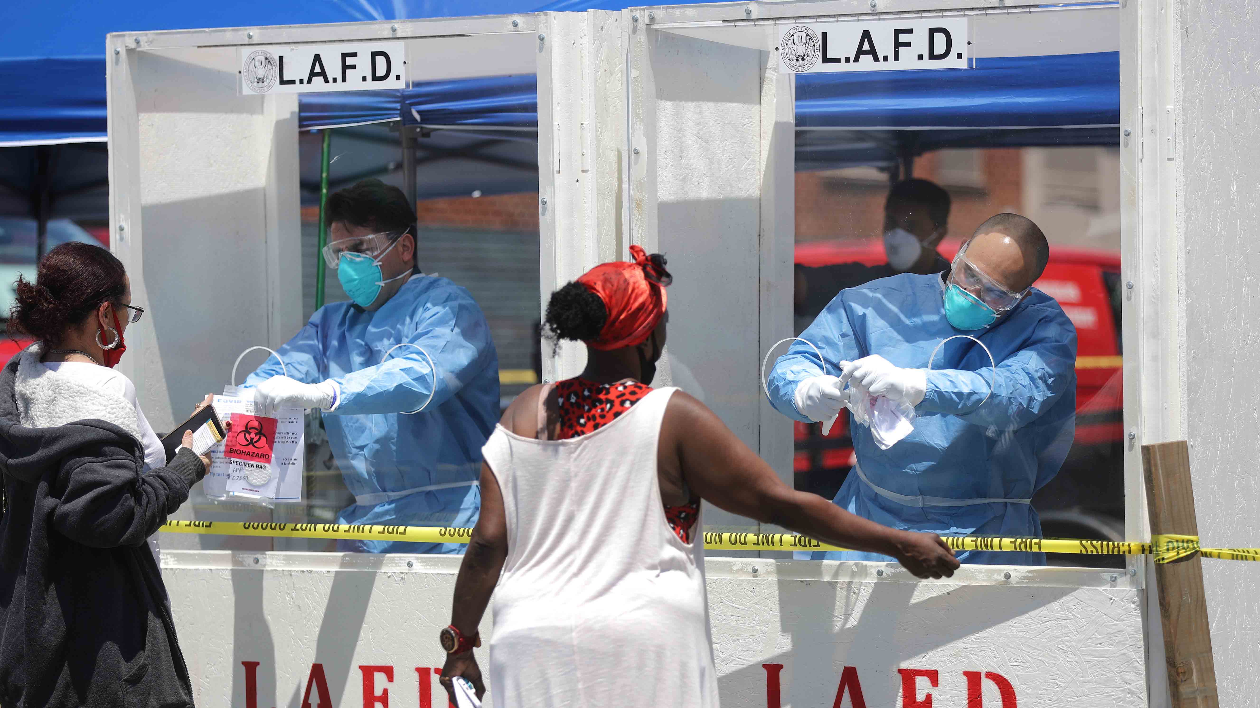LOS ANGELES, CALIFORNIA - APRIL 21: Women are tested for COVID-19 by members of the Los Angeles Fire Department wearing personal protective equipment (PPE) in Skid Row amidst the coronavirus pandemic on April 21, 2020 in Los Angeles, California. Health officials reported that 43 people tested positive for COVID-19 at one Skid Row homeless shelter. (Photo by Mario Tama/Getty Images)