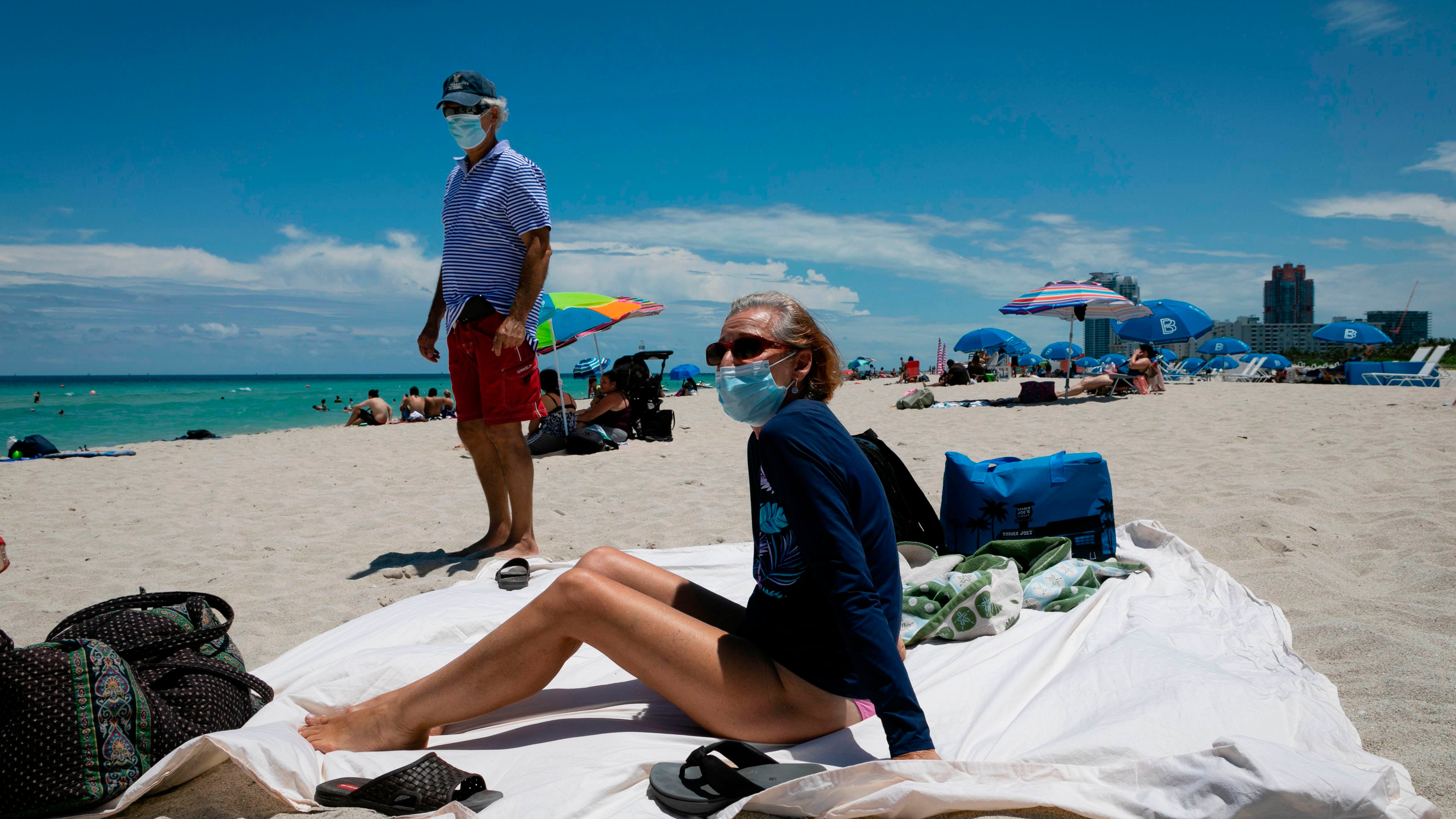 Diane, a nurse from Houston, Texas, sunbathes at the beach next to her husband, both wearing facemasks, in Miami Beach, Florida on June 16, 2020. - Florida is reporting record daily totals of new coronavirus cases, but you'd never know it looking at the Sunshine State's increasingly busy beaches and hotels. (Photo by Eva Marie UZCATEGUI / AFP) (Photo by EVA MARIE UZCATEGUI/AFP via Getty Images)