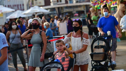 WILDWOOD, NJ - JULY 03: A family waits in line at the entrance to an amusement pier on July 3, 2020 in Wildwood, New Jersey. New Jersey beaches have reopened for the July 4th holiday as some coronavirus restrictions have been lifted, along with casinos, amusement rides and water parks at limited capacity. (Photo by Mark Makela/Getty Images)