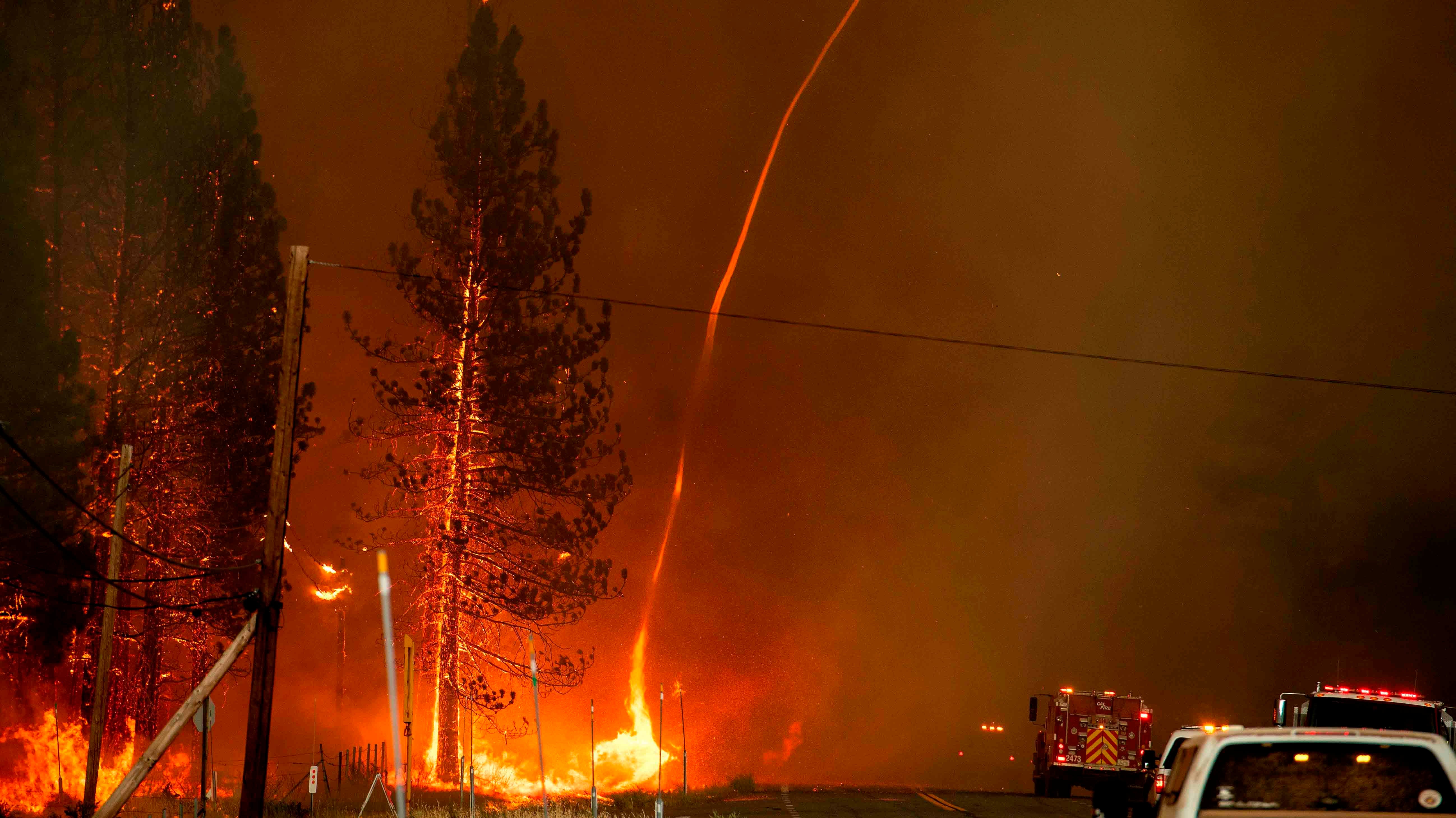 A fire whirl shoots into the sky as flames from the Hog fire jump highway 36 about 5 miles from Susanville, California on July 20, 2020. - The fire exploded to more than 6,000 acres and created its own weather, generating lightning, thunder, rain and fire whirls out of a huge pyrocumulonimbus ash plume towering above. The Lassen County Sheriff's office issued a mandatory evacuation order for the area. (Photo by JOSH EDELSON / AFP) (Photo by JOSH EDELSON/AFP via Getty Images)