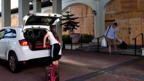 Gio Radziski(L),and Stephen Creitz,leave the Hotel Galvez &Spa where they work and had taken shelter from Hurricane Laura in Galveston,Texas on August 27,2020. - Hurricane Laura slammed into the southern US state of Louisiana Thursday and the monster category 4 storm prompted warnings of "unsurvivable"ocean surges and evacuation orders for hundreds of thousands of Gulf Coast residents. The National Hurricane Center (NHC) said "extremely dangerous"Laura would bring winds of 150 miles per hour (240 kilometers per hour) and "destructive waves will cause catastrophic damage"to Louisiana and Texas. (Photo by Ellie CHERRYHOMES / AFP) (Photo by ELLIE CHERRYHOMES/AFP via Getty Images)