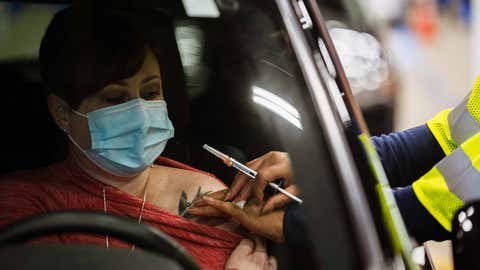 LOUISVILLE, KY - JANUARY 04: A health worker administers a vaccine to a patient while in their vehicle during the first day of mass Moderna COVID-19 vaccinations in Broadbent Arena at the Kentucky State Fair and Exposition Center on January 4, 2021 in Louisville, Kentucky. Monday marked the first day of mass, drive-in vaccinations in the state. Healthcare workers are the main focus of vaccinations, as mandated by the federal government. (Photo by Jon Cherry/Getty Images)