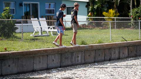 MADEIRA BEACH, FL - JULY 21: Local teenagers grimace while thousands of dead fish float in the Boca Ciega Bay located near the mouth of Madeira Beach on July 21, 2021 in Madeira Beach, Florida. Red tide, which is formed by a type of bacteria, has killed several tons of marine life in Florida so far this year.  (Photo by Octavio Jones/Getty Images)