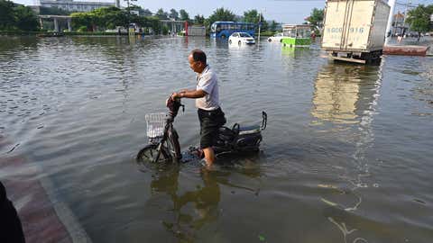 A man rides a motorcycle on a flooded road after heavy rain in Xinxiang, in central Chinas Henan province on July 23, 2021. (Jade Gao/AFP via Getty Images)