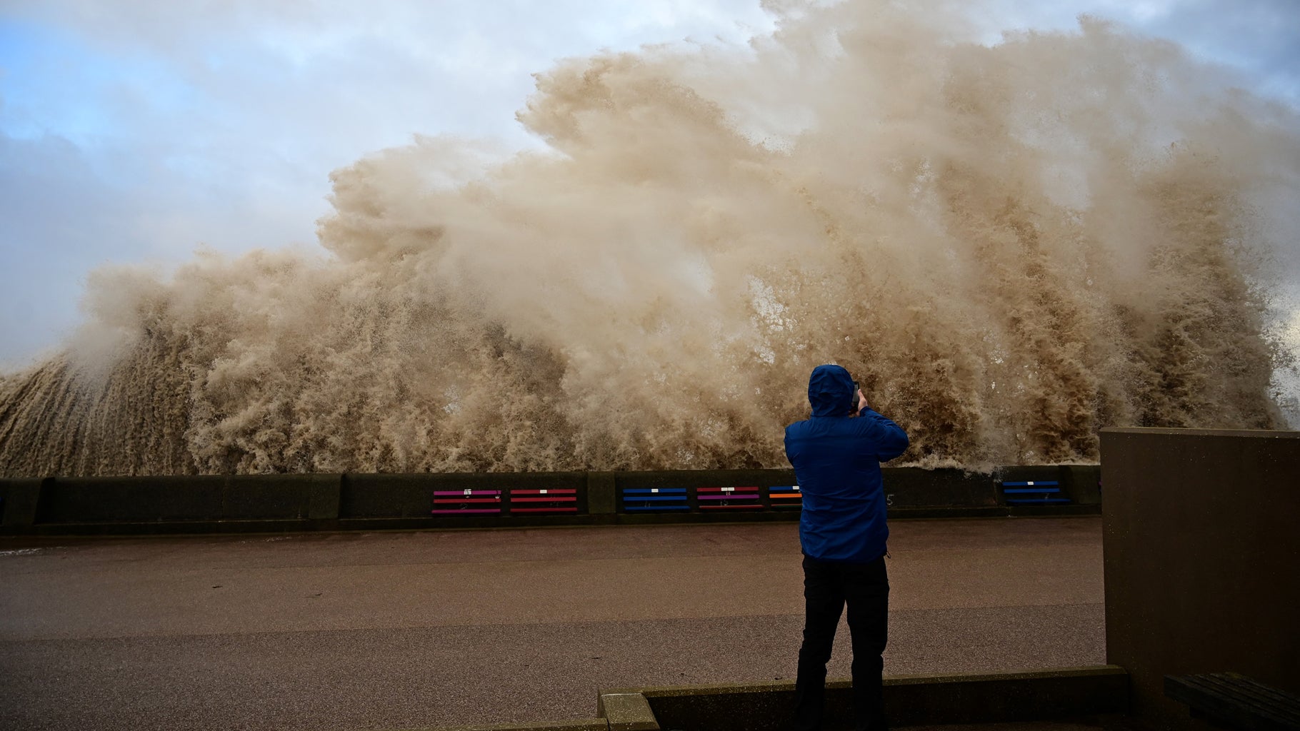 A person takes photographs as waves crash over the promenade in New Brighton, northwest England, on Wednesday, Dec. 8, 2021, as Storm Barra swept over the country. (PAUL ELLIS/AFP via Getty Images)
