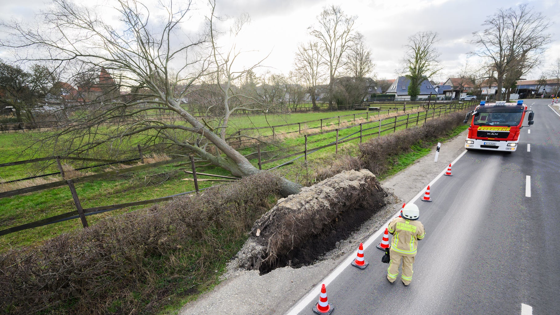 A firefighter stands next to a tree that fell during Storm Dudley on a country road near Wilkenburg, Germany, on Thursday, Feb. 17, 2022. (Photo by Julian Stratenschulte/picture alliance via Getty Images)