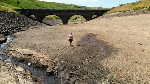 Eine Person geht über ein trockenes Ufer eines Nebenflusses zum Dowry Reservoir in der Nähe von Oldham, während die Hitzewelle in Großbritannien anhält. Bilddatum: Montag, 18. Juli 2022. (Foto von Danny Lawson/PA Images via Getty Images)