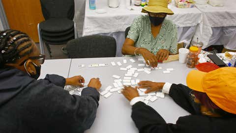 Boston, MA - July 24: Three women play dominoes during their visit to the cooling center at the Grove Hall Senior Center. While Marie Williams, center, kept her hat on, Marilyn Funches-Dooley, left, and Annette Gilbert are bundled up against the cold of the air conditioning. (Photo by Pat Greenhouse/The Boston Globe via Getty Images)