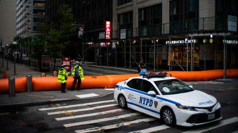 NYPD officers stand guard next to flood barriers used to prevent flooding at the South Street Seaport as the city gets ready for tropical storm Isaias on Aug. 4, 2020, in New York City. The interlocking tubes called Tiger Dams are installed in areas that were heavily damaged from flooding during Hurricane Sandy. (Eduardo MunozAlvarez/VIEWpress via Getty Images)