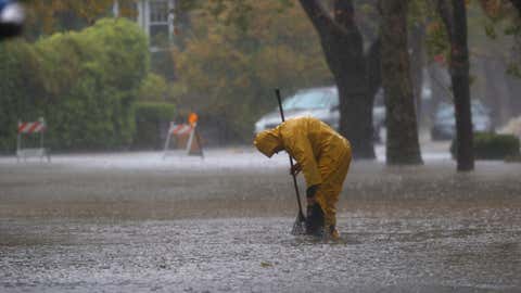 A worker attempts to clear a drain in a flooded street on Oct. 24, 2021, in San Rafael, Calif. A category 5 atmospheric river is bringing heavy precipitation, high winds and power outages to the San Francisco Bay Area. The storm is expected to bring anywhere between 2 to 5 inches of rain to many parts of the area. (Justin Sullivan/Getty Images)