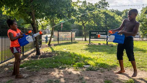 HOUSTON, TEXAS - JUNE 10: Cousins Nai Nai, 5, and CJ Roberts, 7, have a water gun fight at a park near their home on June 10, 2022 in Houston, Texas. Texas is under a heatwave alert as portions of the state are projected to see record high temperatures throughout the weekend. (Photo by Brandon Bell/Getty Images)