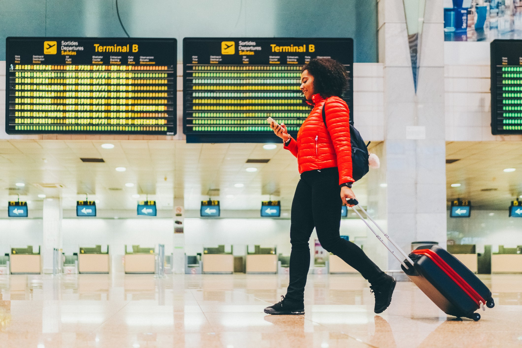 Tourist with suitcase at the airport walking and texting