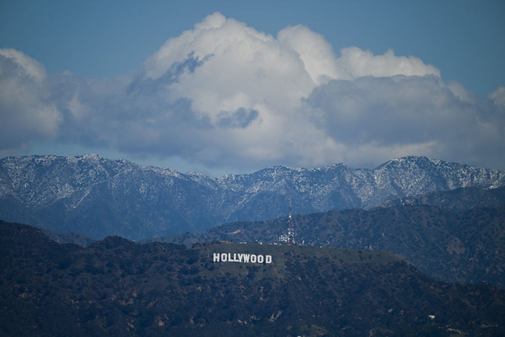 Snow dusted mountains stand on the skyline behind a view of the Hollywood sign following rain storms, as seen from the Kenneth Hahn State Recreation Area, in Los Angeles, California on March 7, 2025. (Photo by Patrick T. Fallon / AFP) (Photo by PATRICK T. FALLON/AFP via Getty Images)