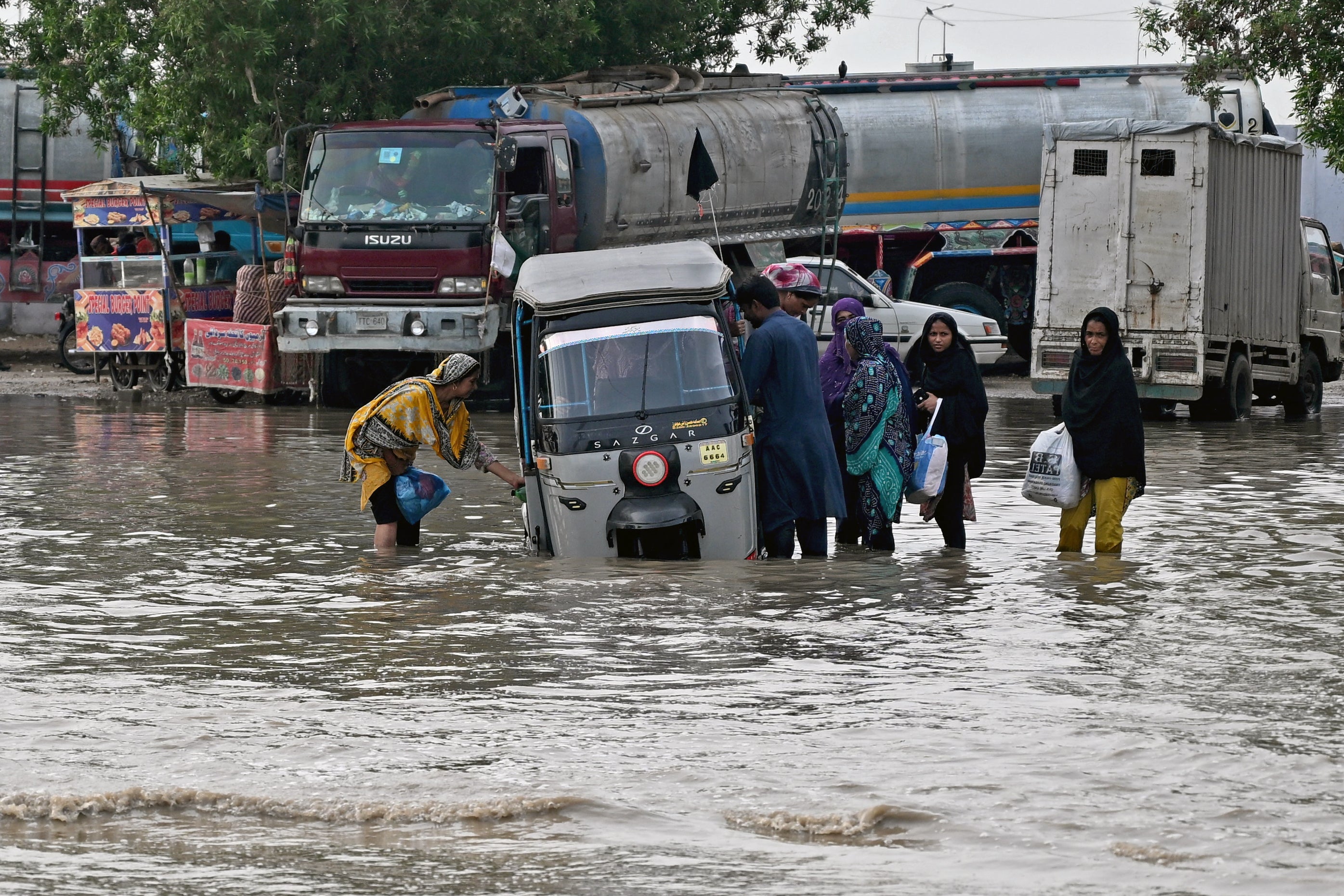 Passengers disembark from an auto rickshaw that got stranded on a flooded road after heavy monsoon rains in Karachi on August 20, 2025. More than 20 people died in a fresh spell of deadly monsoon rain in Pakistan, National Disaster Management Agency (NDMA) said on August 20. (Photo by Rizwan TABASSUM / AFP) (Photo by RIZWAN TABASSUM/AFP via Getty Images)          