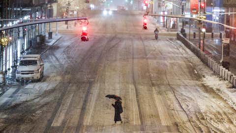 A woman crosses a street near Manhattan's Grand Central during a snowfall in New York City on Feb. 22, 2026. (Photo by CHARLY TRIBALLEAU/AFP via Getty Images)